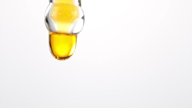 Super Slow Motion Detail Shot of Oil Drop from Dropper Isolated on White Background at 1000fps.