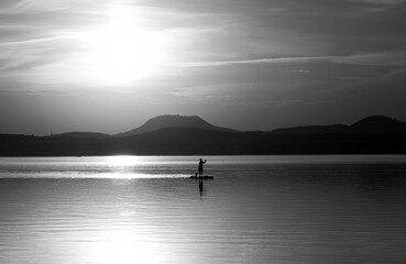 Obraz na płótnie Canvas a young man doing paddleboarding on the lake