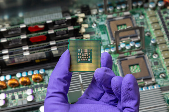 installing a new processor in a computer, gloved hand holds a cpu against the background of computer parts