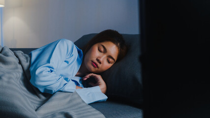 Happy young Asian lady asleep on sofa alone in living room while watching movie or sport in tv late at home at night. Snoring person, Social distancing, quarantine for coronavirus prevention concept.