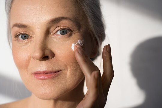 Female person applying rejuvenation cream on face with her hand