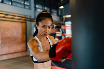 Young Asia lady kickboxing exercise workout punching bag tough female fighter practice boxing in...