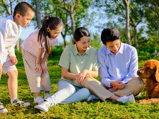 Happy family of four and pet dog playing in the park