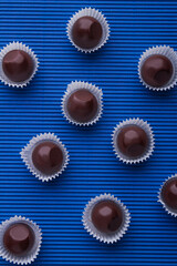 Vertical shot sweet brown chocolate candies on blue background.