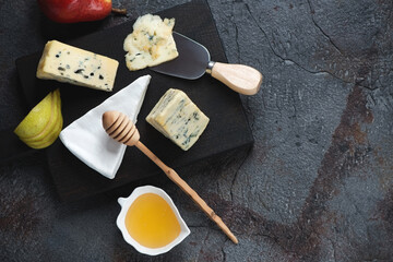 Blue and brie cheese with pier slices and honey, above view on a grey asphalt background, horizontal shot with space