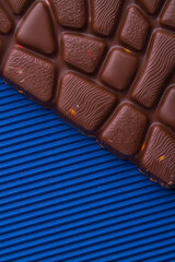 Close-up brown milk chocolate bar on blue background.