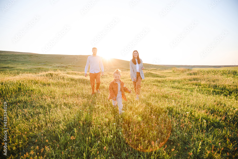 Wall mural A hipster family walks in a summer field.