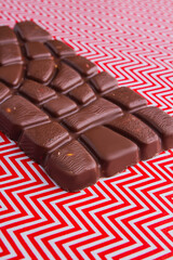 Vertical shot brown chocolate bar on white and red background.