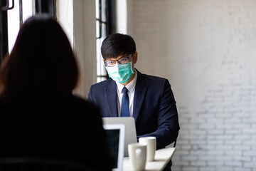 Attractive businesswoman and man manager are colleagues working on laptop computer together in office. face mask prevent covid-19 virus