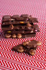 Vertical shot cut pieces of chocolate bar with hazelnuts and fruits.