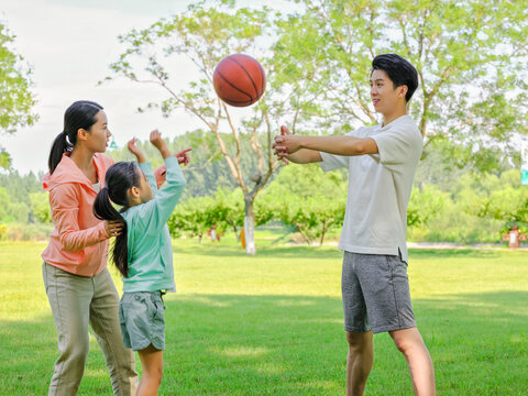 Happy family of three playing basketball in the park