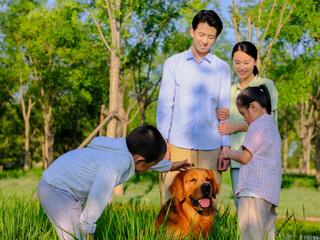 Happy family of four and pet dog playing in the park