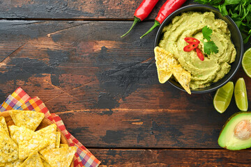Guacamole. Traditional latinamerican Mexican dip sauce in a black bowl with avocado and ingredients...
