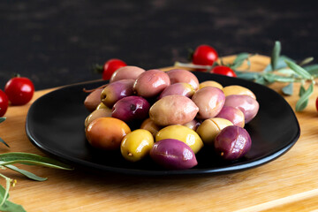 Mixed marinated olives (green and purple). Tasty colored olives in the plate.