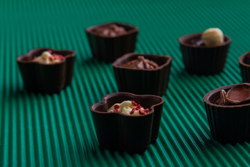 Close-up sweet chocolate candies on relief green background.