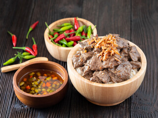 Thai food, Rice topped with pork liver and garlice in wooden bowl on brown wooden table. Favorite food in Thailand.