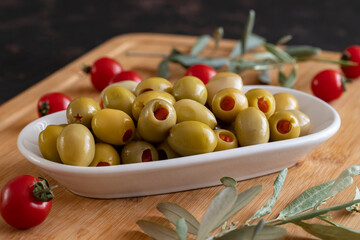 Green olives stuffed with peppers. Tasty organic green olives in the plate. Olives on wooden background