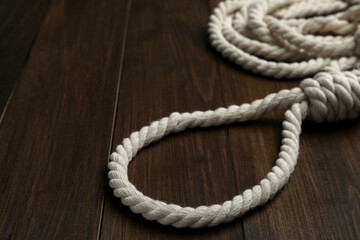 Rope noose on wooden table, closeup view