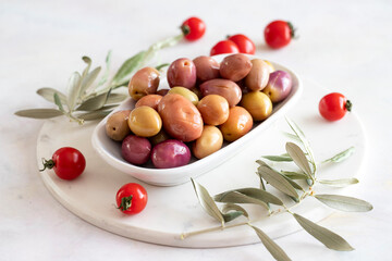 Pink and Purple kalamata olives. Tasty organic colored kalamata olives in the plate. Olive on marble floor
