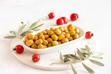 Scratched yellow olives. Tasty organic yellow olives in the plate. Olive on marble floor