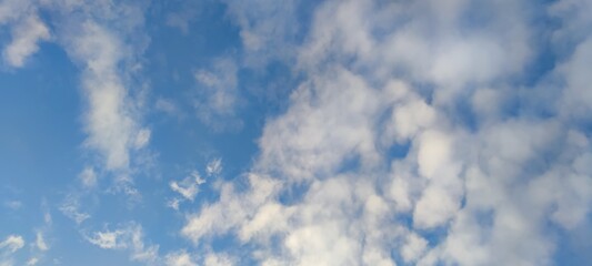 Light white cloud against the blue sky. A small, scattered white cloud floats across the sky next to the sun. The color of the sky changes from light blue to dark blue.