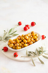 Scratched yellow olives. Tasty organic yellow olives in the plate. Olive on marble floor
