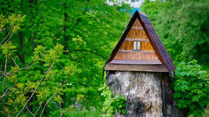 Fototapeta na wymiar house in the forest for animals and birds. Wooden bird house in the summer park. on an tree stump. Old wooden feeder for birds on a tree, empty bird's feeder caring about wild birds in cold season.