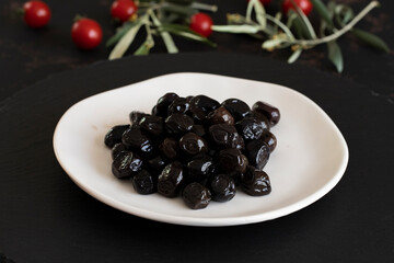 Black olives on a dark background. Tasty black olives in the plate
