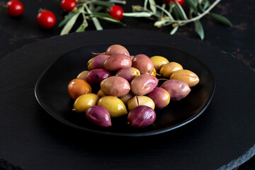 Mixed marinated olives (green and purple) on dark background. Tasty colored olives in the plate