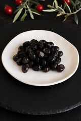 Black olives on a dark background. Tasty black olives in the plate