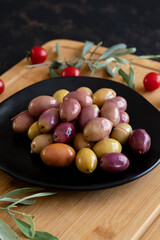 Mixed marinated olives (green and purple). Tasty colored olives in the plate.