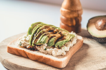 Slice of bread with avocado and cheese with pepper on a wood.