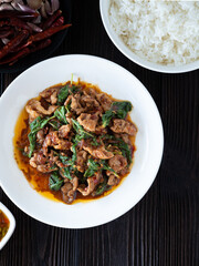 Thai food, Stir fried pork and basil in white plate on brown wooden table. Favorite food in Thailand.