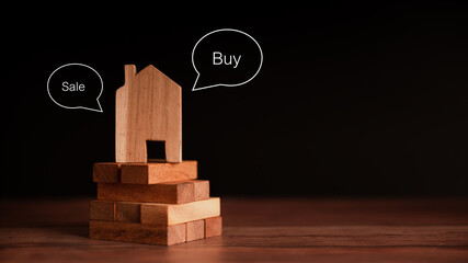 Blog wooden house set on a pile of wooden blocks. Black background. Investment concept buy-sale real estate business.