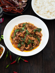 Thai food, Stir fried pork and basil in white plate on brown wooden table. Favorite food in Thailand.