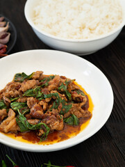 Thai food, Stir fried pork and basil in white plate on brown wooden table. Favorite food in Thailand.