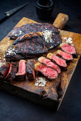 Traditional barbecue dry aged wagyu Brazilian picanha steaks from the sirloin cap of rump beef sliced and served as close-up on a rustic wooden board