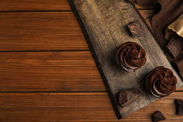 Fototapeta premium Flat lay composition with delicious chocolate cupcakes on wooden table. Space for text