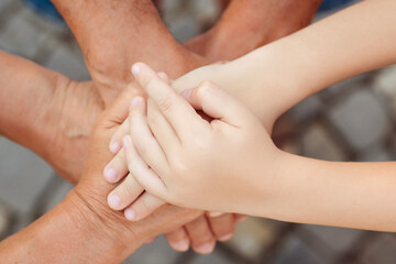 Fototapeta premium Grandparents with grandchild holding hands together, top view. Family, care and support concept.