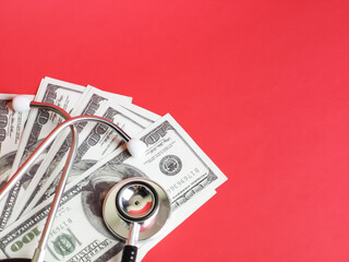 Health care cost concept. Red background with stethoscope, fake money and copy space.