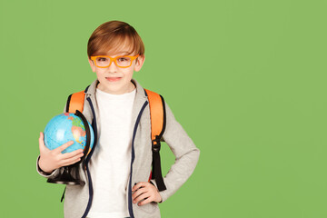 School boy with globe isolated over green background. Smart boy studying geography. Back to school concept.