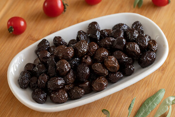 Black olive. Tasty organic black olives in the plate. Olives on wooden background