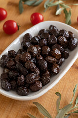 Black olive. Tasty organic black olives in the plate. Olives on wooden background