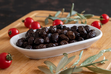 Black olive. Tasty organic black olives in the plate. Olives on wooden background