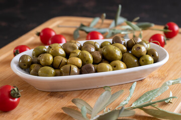 Scratched green olives. Tasty organic green olives in the plate. Olives on wooden background