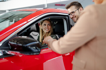 Woman manager consulting young beautiful woman client while looking for new car in dealership center