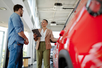 Handsome man with car dealer in auto show or salon.