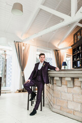 Bridegroom posing before the wedding ceremony at the background of classic interior