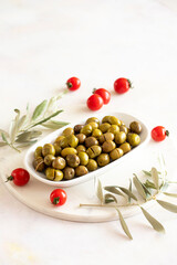 Scratched green olives. Tasty organic green olives in the plate. Olive on marble floor