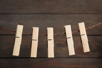 Many clothespins on rope against wooden background